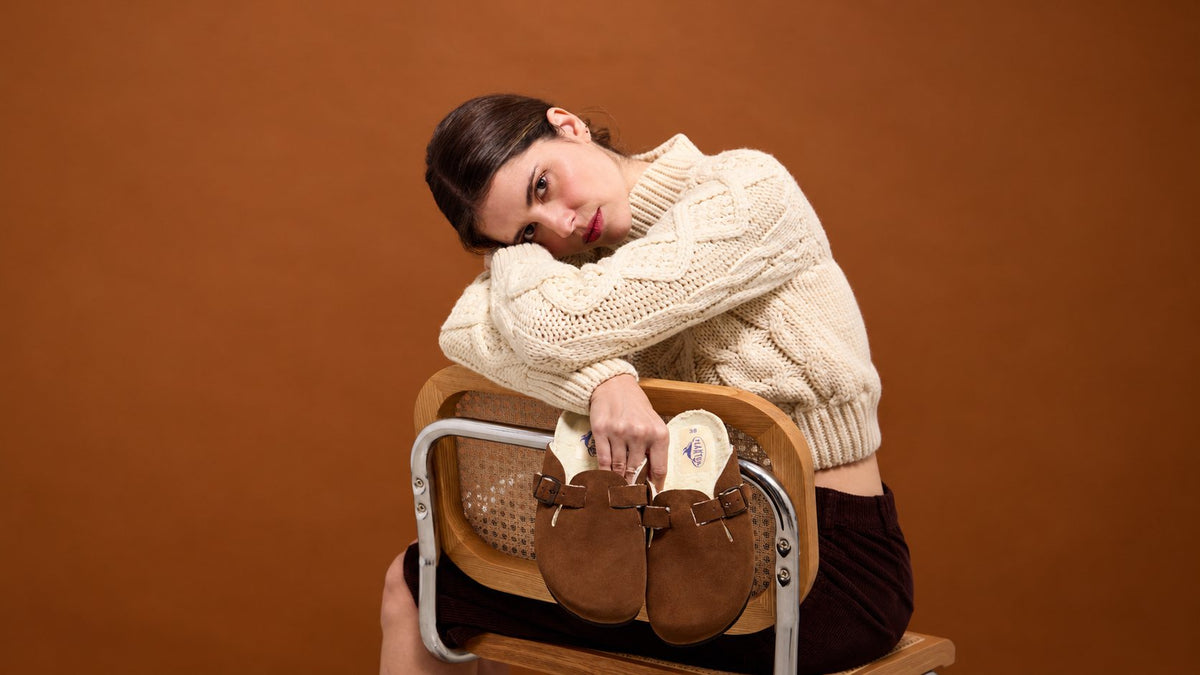 Woman sitting with a pair of brown wool-lined Plakton Home clogs